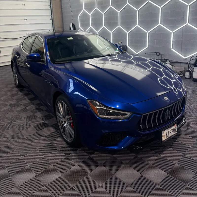 Deep blue Maserati with Level One ceramic coating under hexagonal shop lights
