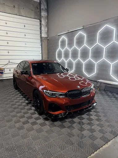 Burnt orange BMW sedan with ceramic window tint under hexagonal shop lights in Chantilly