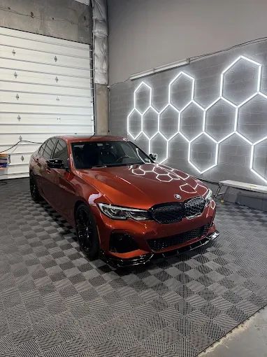 Burnt orange BMW sedan with ceramic window tint under hexagonal shop lights in Chantilly