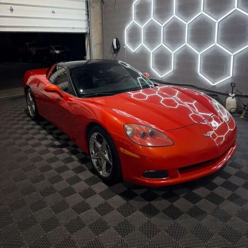 Orange Corvette C6 coupe with mirror ceramic finish reflecting hexagonal shop lights