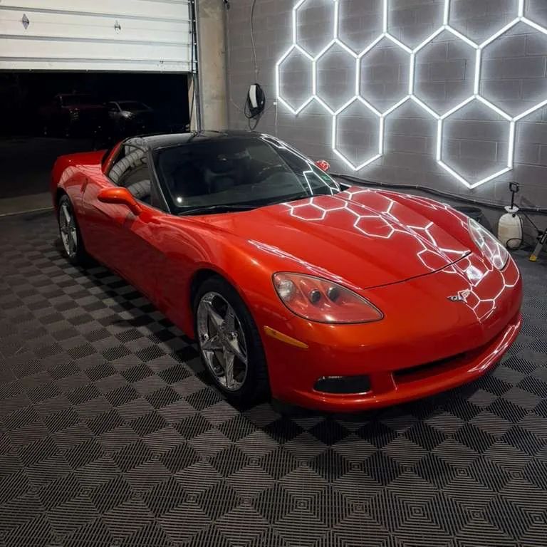 Orange Corvette C6 coupe with mirror ceramic finish reflecting hexagonal shop lights