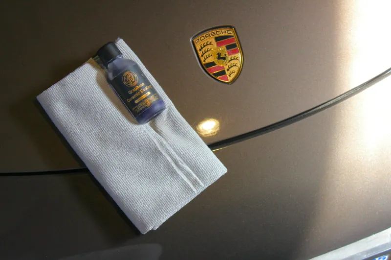 Graphene ceramic coating bottle on a microfiber cloth on a Porsche hood