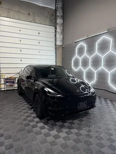 Black Tesla Model Y with paint protection finish under hexagonal shop lights in Chantilly