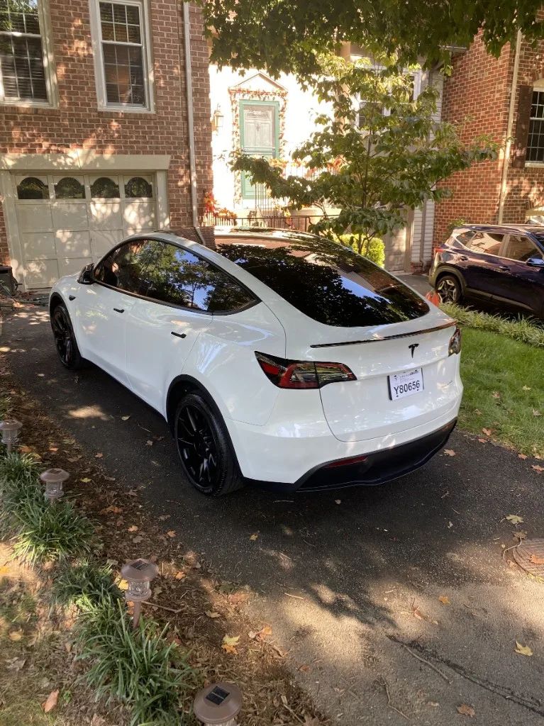 White Tesla Model Y with dark window tint and glossy paint protection on a driveway
